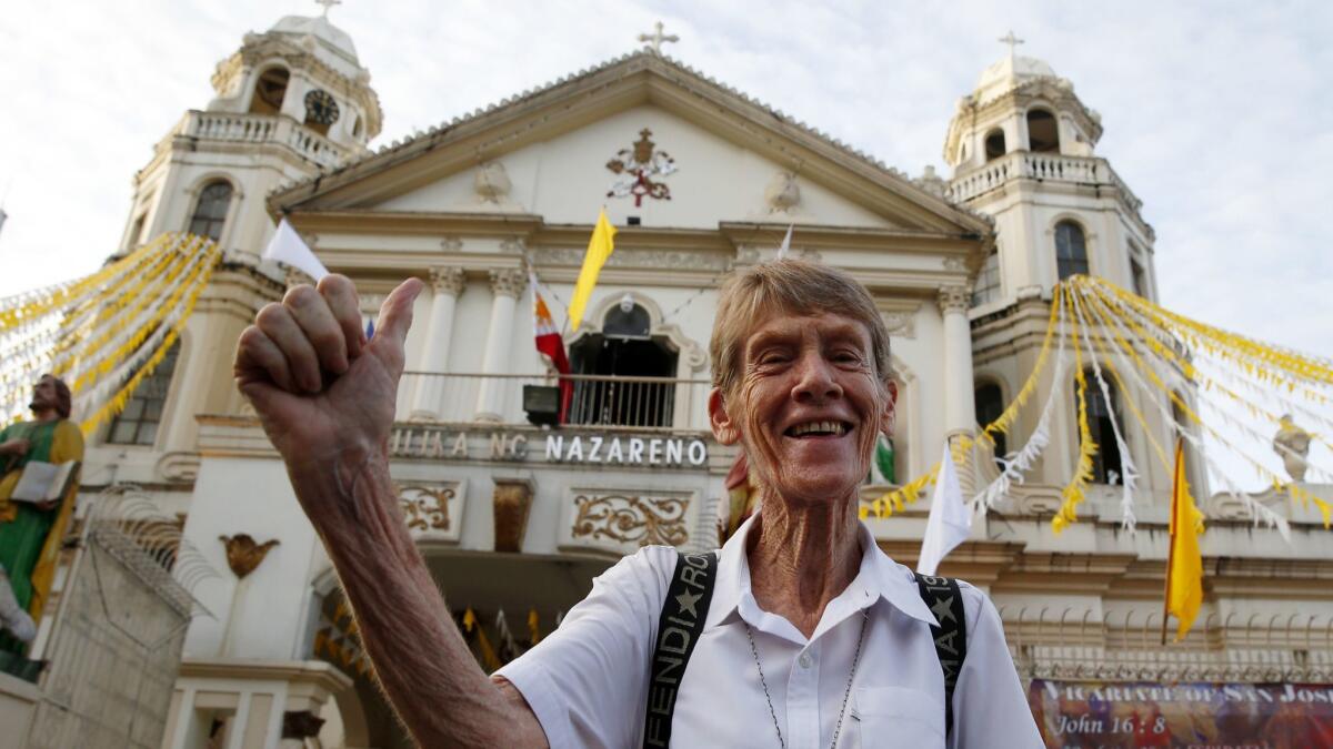 Sister Patricia Fox flashes the thumbs up sign June 18 as she arrives for a protest in Manila days after a Catholic priest was shot to death in a chapel while preparing for Mass.