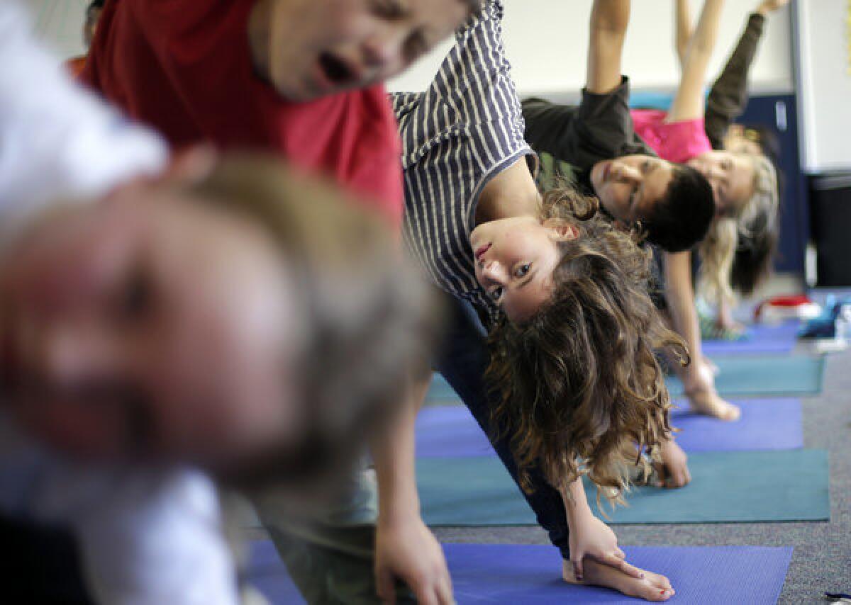 Students hold a position during a yoga class at Capri Elementary School in Encinitas. A judge has ruled against a claim that teach yoga in Encinitas schools does not amount to religious instruction and can continue.