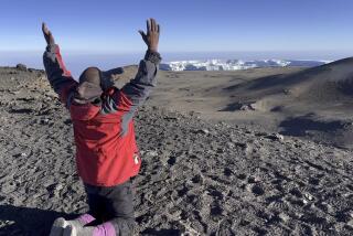 Guide Andrew Mafie offers a prayer of gratitude on the 19,341-foot summit of Mt. Kilimanjaro.