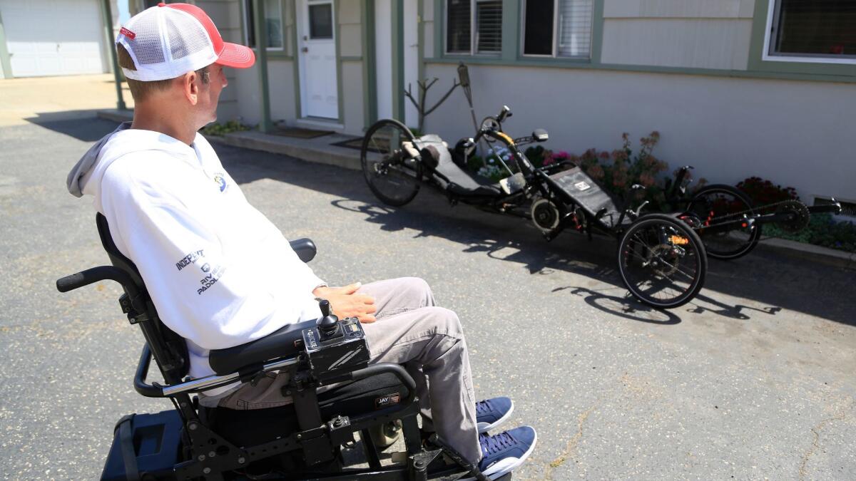 Lance Weir looks over his modified cycle, nicknamed Excalibur, at his home in Carlsbad. Weir is a C-5 quadriplegic who is half of the first tandem hand-cycle team to compete in an Ironman event this weekend in Oceanside.