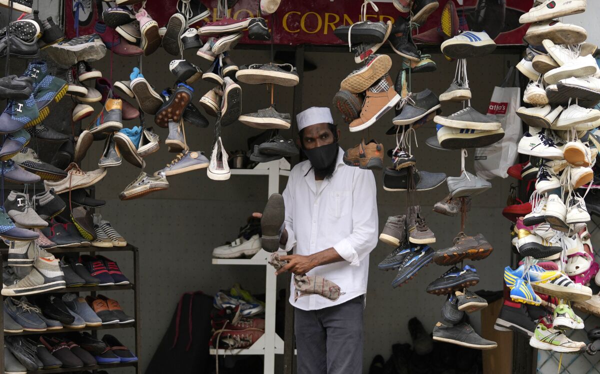 A Sri Lankan man displays used shoes for sale at his shop after easing of restrictions that were imposed to curb the spread of the coronavirus in Colombo, Sri Lanka, Friday, Oct. 1, 2021. Sri Lanka lifted a six-week lockdown Friday as COVID-19 cases and deaths decline but will restrict people's movement for work and obtaining essentials only which are running short in the island country amid economic worries. (AP Photo/Eranga Jayawardena)