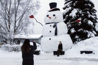 FILE - Isil Mico takes a photo of her sister-in-law Oznur Mico in front of Snowzilla, a snowman measuring more than 20 feet tall, in Anchorage, Alaska on Jan. 10, 2024. A recent storm dropped nearly 16 inches of snow on Anchorage, bringing the seasonal total to over 103 inches. It’s the earliest Alaska’s largest city has reached the 100-inch mark. (AP Photo/Mark Thiessen, File)