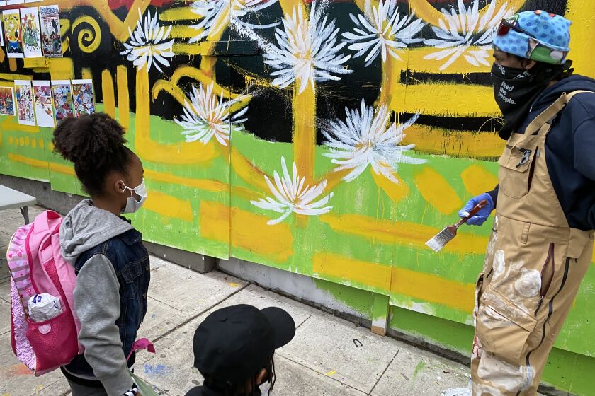 Malcolm Procter pauses to talk with children viewing a mural he's painting on plywood in the "autonomous zone" where Seattle police vacated a precinct amid protests and left the district to activists who proclaimed the area an "autonomous zone."