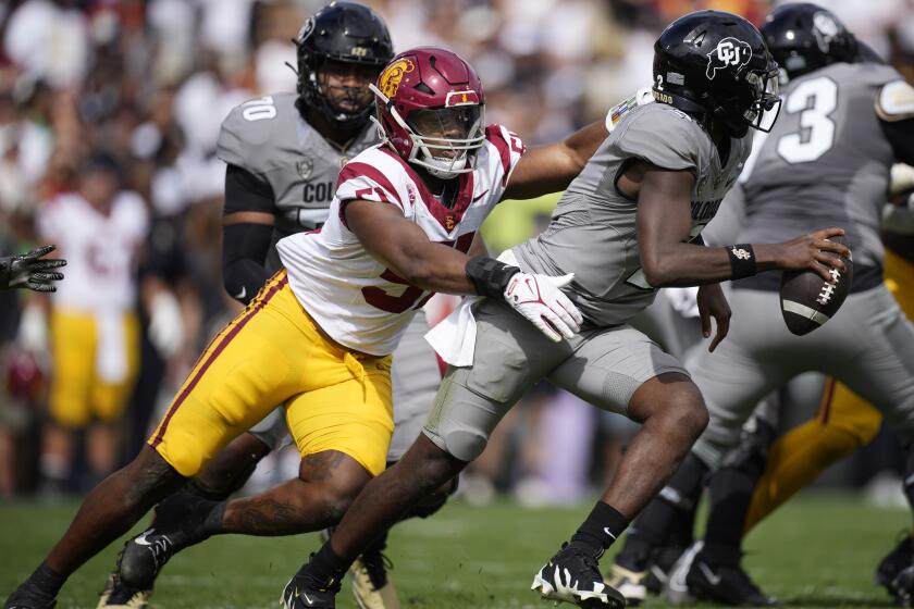 Southern California linebacker Theo Bravos, left, pursues Colorado quarterback Shedeur Sanders in the second half of an NCAA college football game, Saturday, Sept. 30, 2023, in Boulder, Colo. (AP Photo/David Zalubowski)