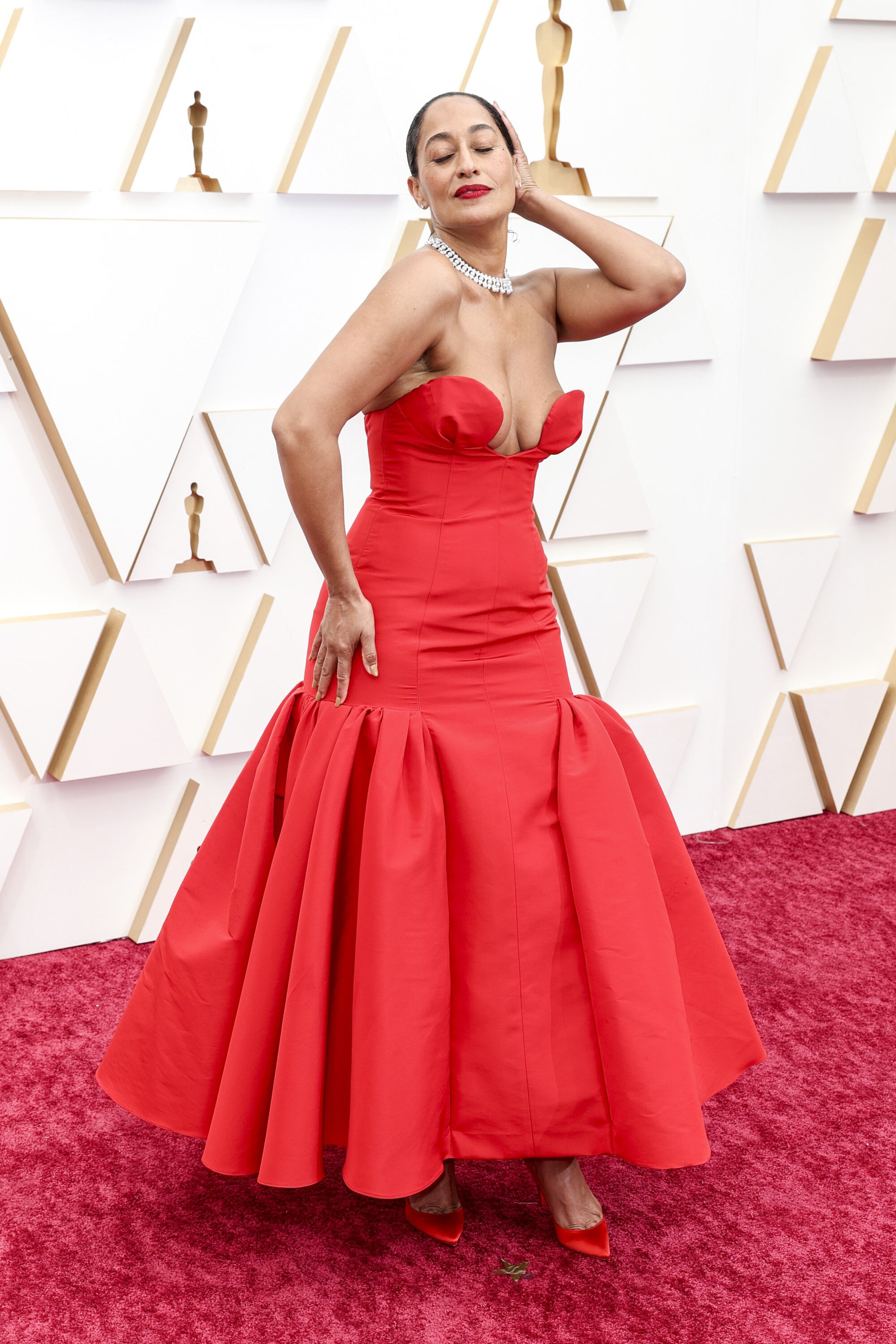 A woman shows off her red gown on the red carpet at the Oscars 2022.