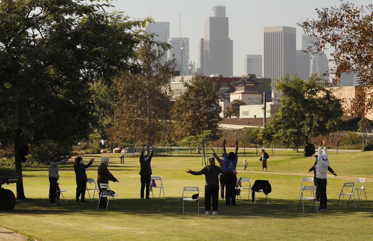 A group of people in a spaced-out circle at a park with downtown L.A. skyline in the background