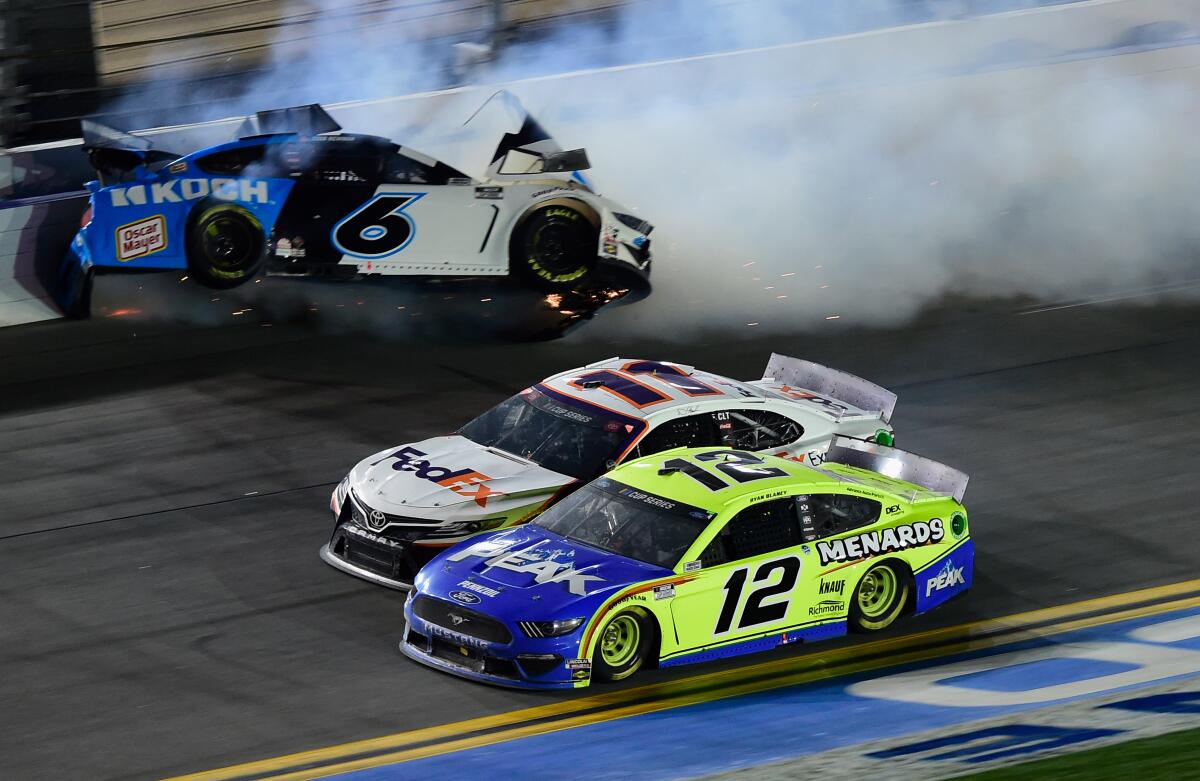 Ryan Newman hits the outside wall as Denny Hamlin, center, beats Ryan Blaney to the finish line to win the Daytona 500 on Monday.