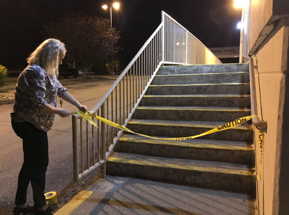 Loretta Simon, chief nursing officer, puts up caution tape outside the ER after her last shift at the now-defunct Williamson Memorial Hospital in Williamson, W.Va.