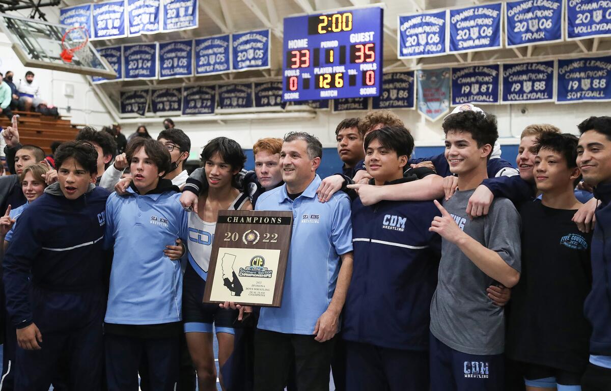 CdM coach Mark Alex holds the championship trophy with his team after winning the CIF Duals Division 6 wrestling title.