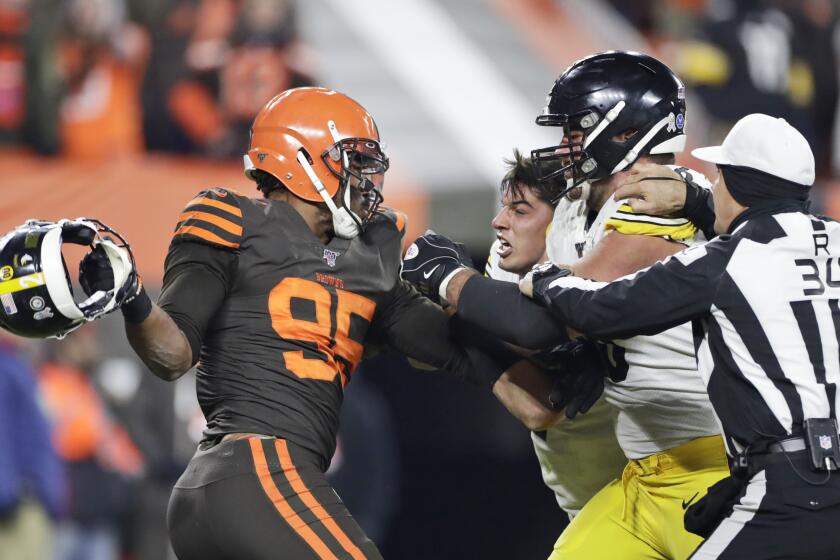 Cleveland Browns defensive end Myles Garrett, left, gets ready to hit Pittsburgh Steelers quarterback Mason Rudolph, second from left, with a helmet during the second half of an NFL football game Thursday, Nov. 14, 2019, in Cleveland. The Browns won 21-7. (AP Photo/Ron Schwane)