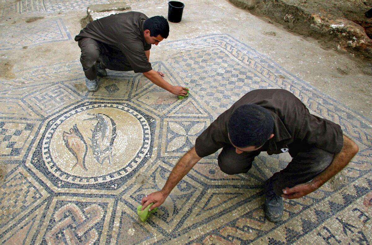 Men working on a nearly 1,800-year-old mosaic floor in Megiddo, Israel