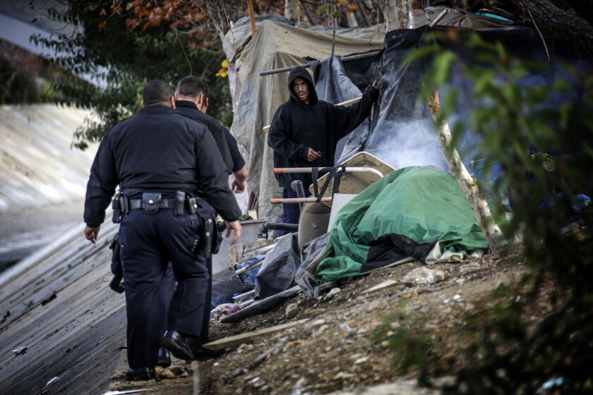 LAPD officers approach a homeless man camped along the Arroyo Seco on January 13.