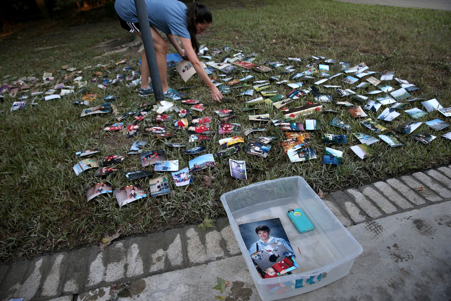 Katie Estridge organizes hundreds of soaked family photographs on the front lawn of her father's home in northeast Houston.