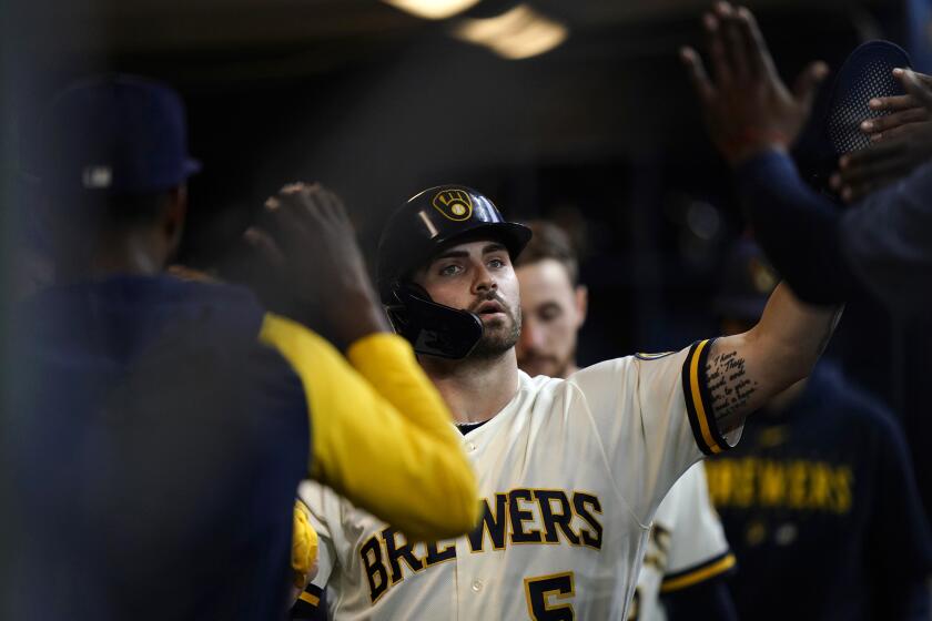 Milwaukee Brewers' Garrett Mitchell is congratulated in the dugout after scoring a run during the third inning of a baseball game against the St. Louis Cardinals, Thursday, Sept. 28, 2023, in Milwaukee. (AP Photo/Aaron Gash)