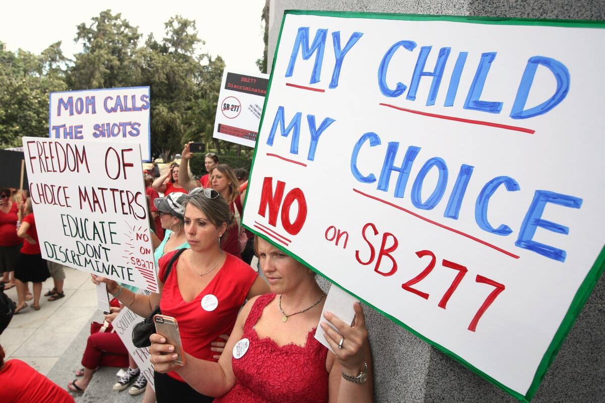 Karman Willmer, left, and Shelby Messenger protest against SB 277, a measure requiring California schoolchildren to get vaccinated, at a Capitol rally on June 9 in Sacramento.