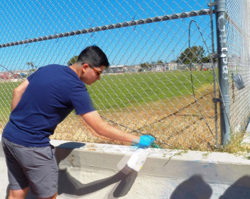 Rotaract member Erick Ramirez removing graffiti.