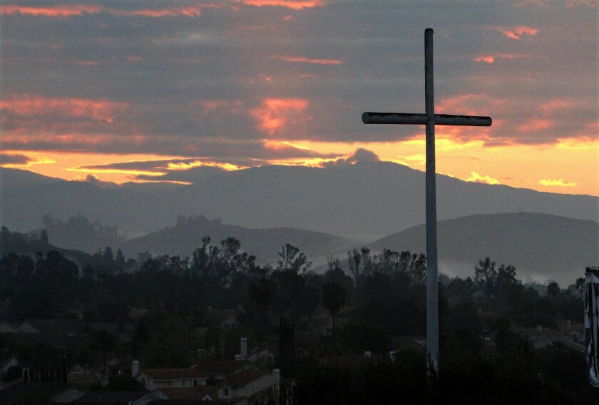 A cross on the property of the Gateway Church of the Nazarene stands in the foreground of the sunrise during the church's Easter sunrise service in Murrieta.