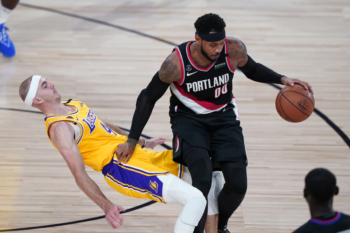 Lakers guard Alex Caruso falls to the court defending Portland Trail Blazers forward Carmelo Anthony.