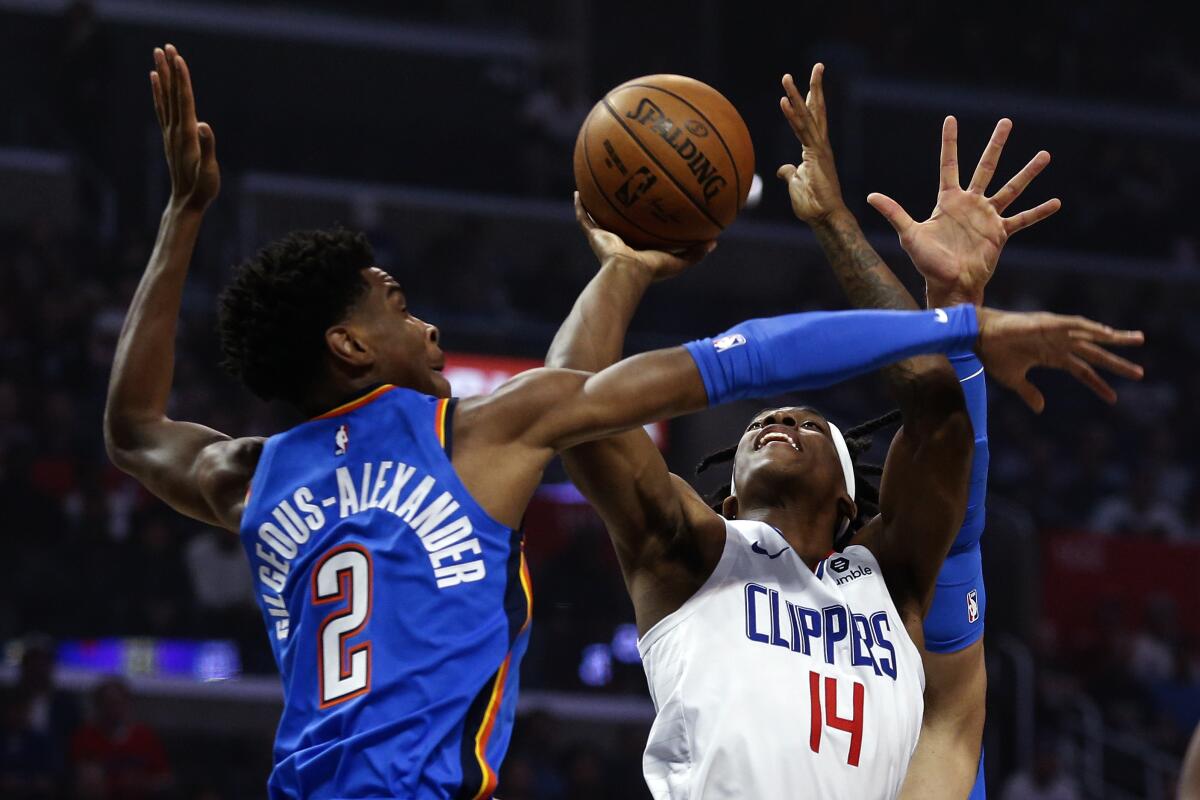 Clippers guard Terance Mann (14) shoots under pressure from Thunder guard Shai Gilgeous-Alexander (2) during the first half of a game Nov. 18 at Staples Center.