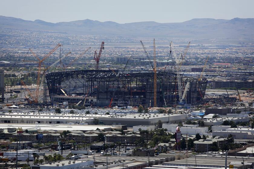 FILE - In this June 4, 2019, file photo, construction cranes surround the football stadium under construction in Las Vegas. Officials in Las Vegas have boosted the cost of a 65,000-seat stadium being built for the NFL's relocated Raiders and UNLV football to $1.9 billion. The Las Vegas Review-Journal reports the Las Vegas Stadium Authority board on Thursday, July 18, 2019, approved $40 million in additions. They include 20 more suites and a field-level club area to be paid for by personal seat license and club seat sales not part of the original budget. (AP Photo/John Locher, File)