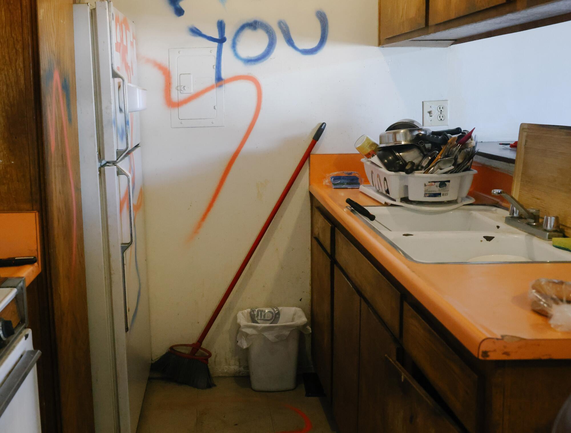 A kitchen spray-painted with graffiti in orange and blue