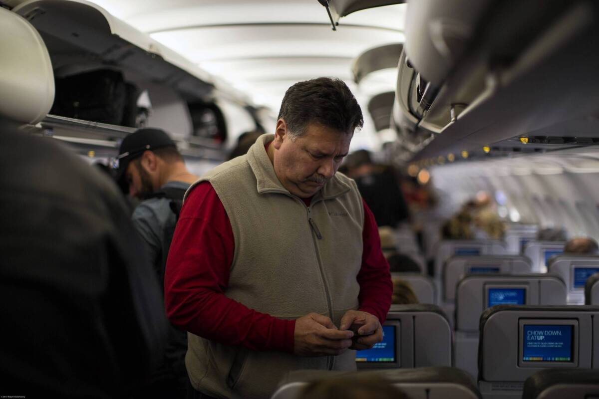 A passenger on a JetBlue Airways flight checks his cellphone before disembarking at Long Beach Airport. Passengers still aren't allowed to do it during takeoffs and landings.