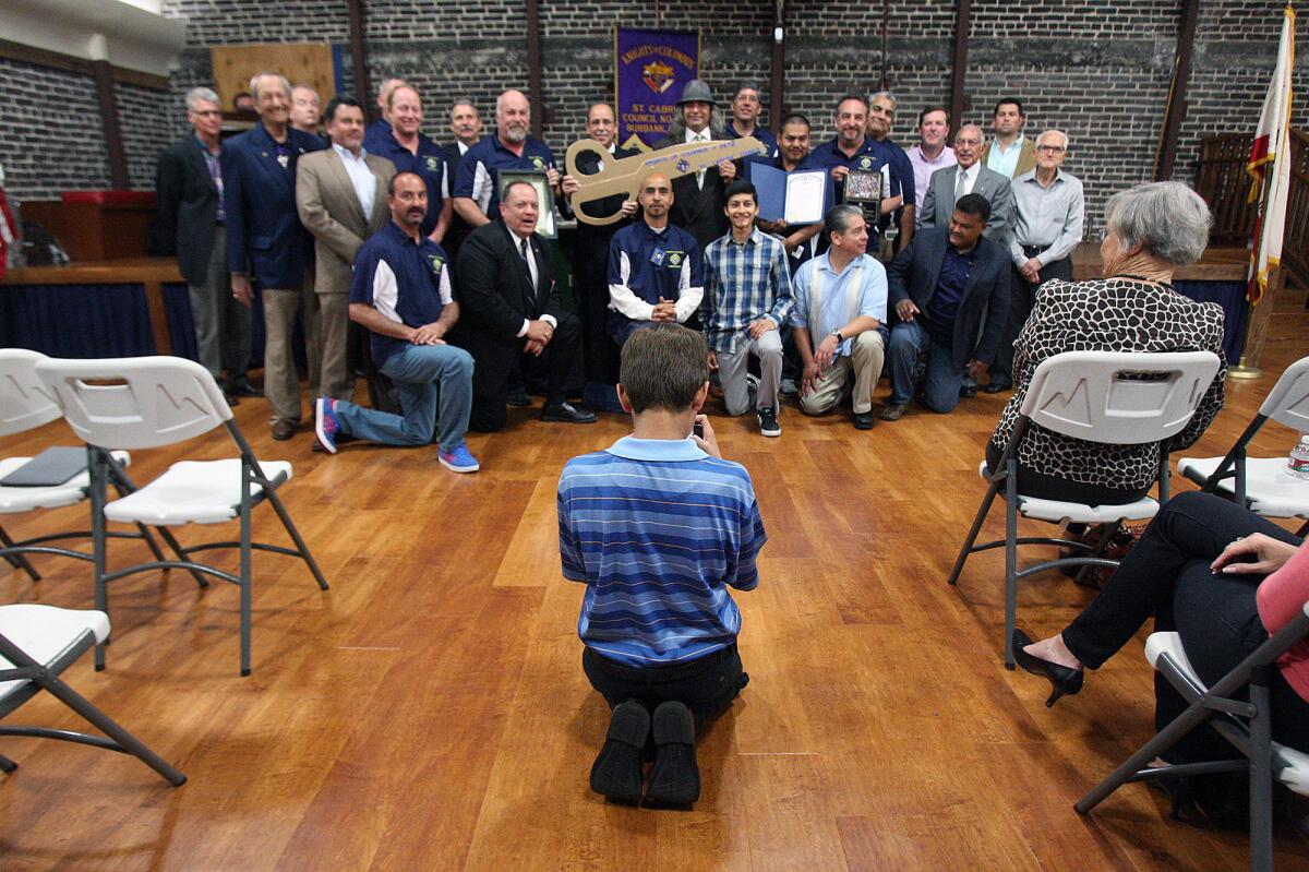 Anthony Chiaravalle, 11, of Burbank, takes a group photo with his iPhone of the Knights who attended the first meeting, and hall rededication ceremony of the Knights of Columbus Saint Cabrini Council in Burbank on Friday, March 21, 2014 since the fire that destroyed the adjacent building and damaged their building in May, 2013.