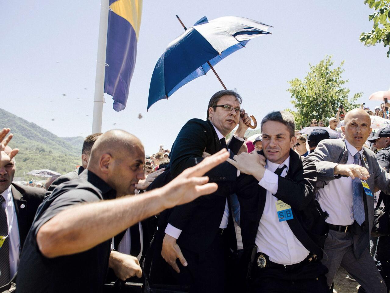 Bodyguards try to protect Serbian Prime Minister Aleksandar Vucic, center, from stones hurled at him by an angry crowd at a commemoration of the 1995 Srebrenica massacre on July 11, 2015, near Srebrenica in Bosnia-Herzegovina.