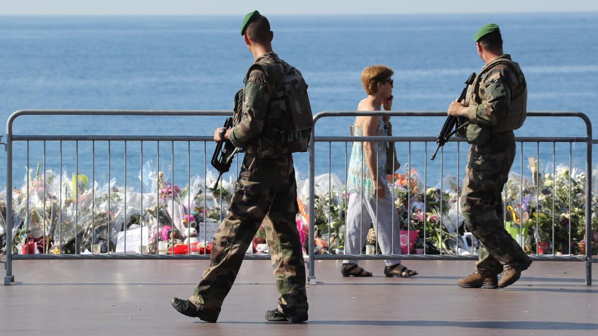 Soldiers on Tuesday pass by the new makeshift memorial for the victims of the Bastille Day attack in Nice, France. The flowers on the Promenade des Anglais were moved closer to the seafront so that the road could be reopened.
