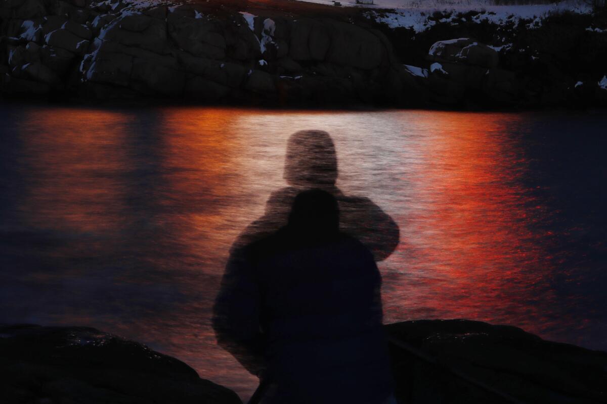 A man is silhouetted against lights reflected in the waters off Cape Neddick in Maine