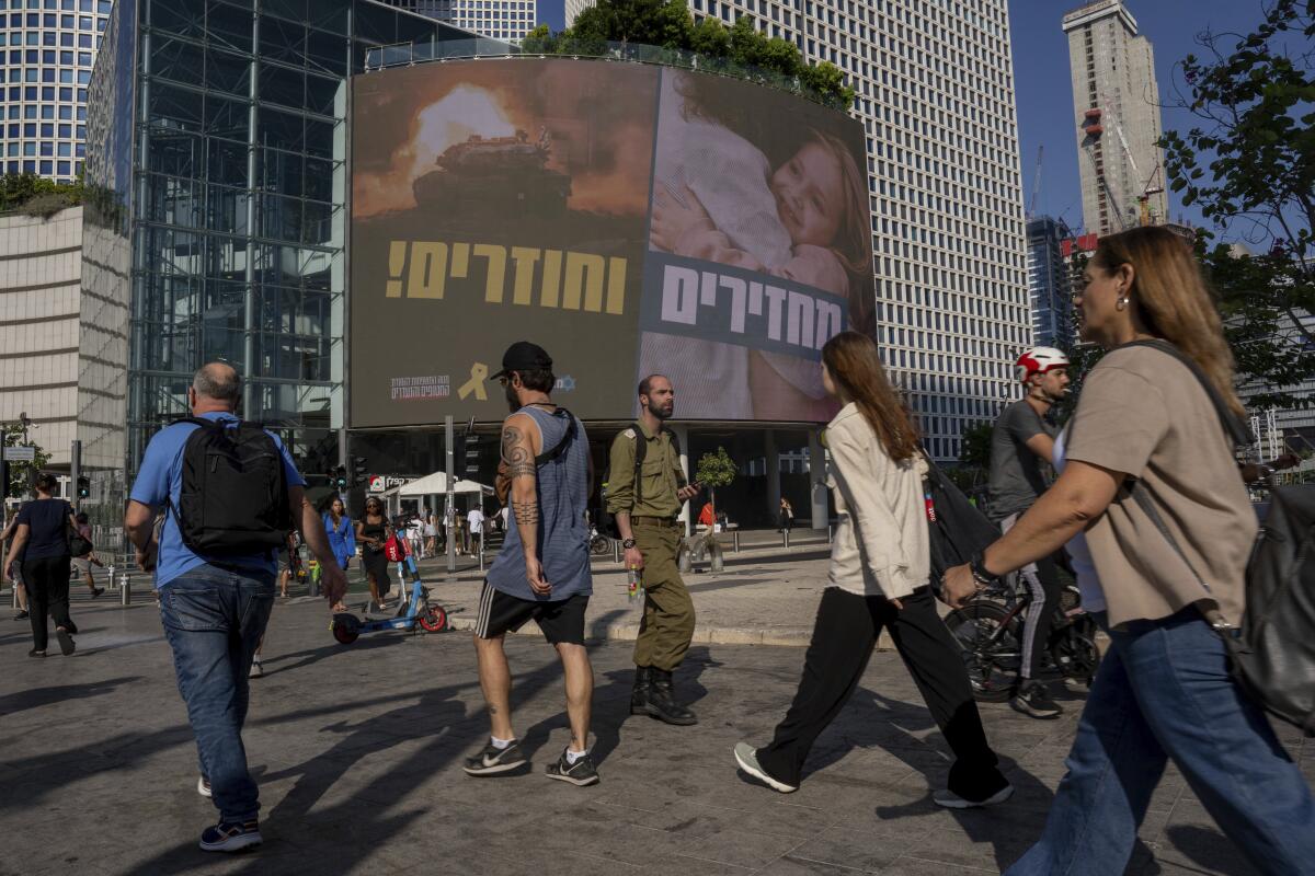 People in Tel Aviv pass by a massive sign calling for the release of hostages held in the Gaza Strip by Hamas.