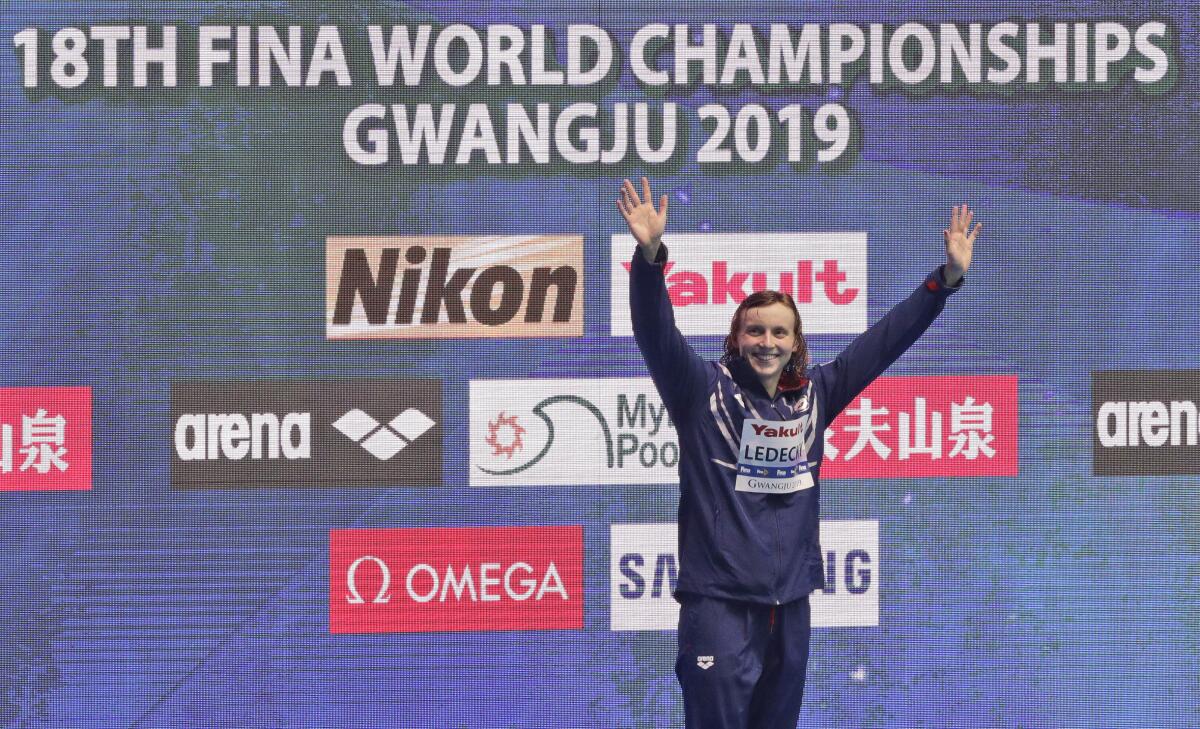 File-This July 27, 2019, file photo shows gold medalist Katie Ledecky of the United States waving on the podium following the women's 800m freestyle final at the World Swimming Championships in Gwangju, South Korea. Like everyone else, Ledecky was forced to shelve her plans when the coronavirus pandemic took hold. Instead of looking far into the future, the five-time Olympic champion swimmer switched to a more immediate mindset. Forget that the four-year cycle leading to the 2024 Paris Olympics is already underway. Ledecky is still working toward making a big splash at this summer's delayed Tokyo Games. (AP Photo/Mark Schiefelbein)