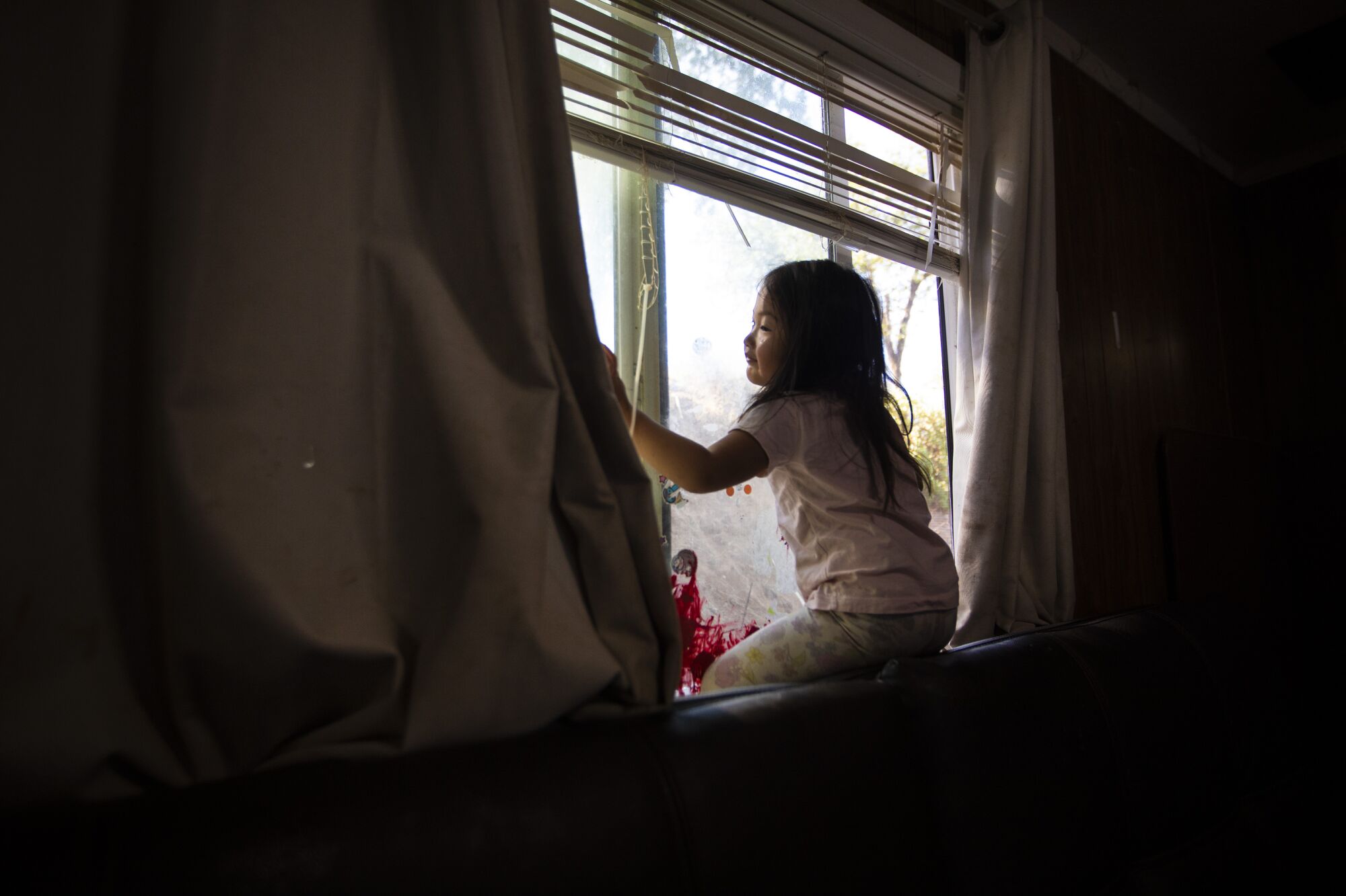 A young girl sits looking out a window 