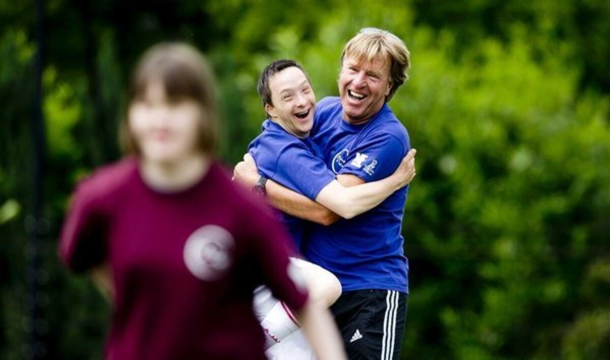 A child with Down syndrome hugs a trainer during a soccer tournament "Give Down a future" in Amsterdam.