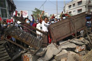 Anti-coup protesters shout slogans behind makeshift barriers in Mandalay, Myanmar, on Sunday.