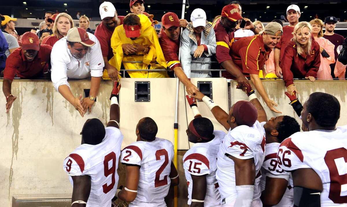 USC football players reach up to the stands to greet family at a game before the pandemic.
