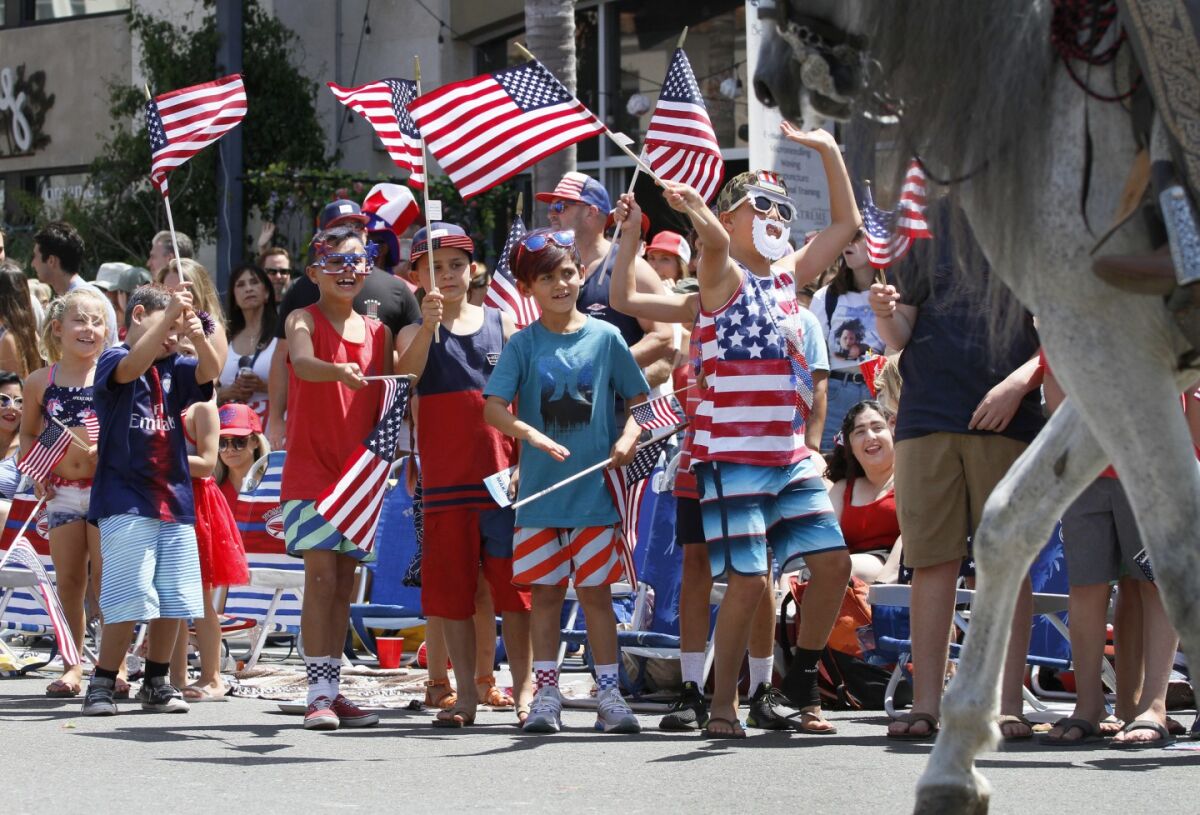 Kids wave American flags on Main Street during Huntington Beach's Fourth of July parade in 2019.