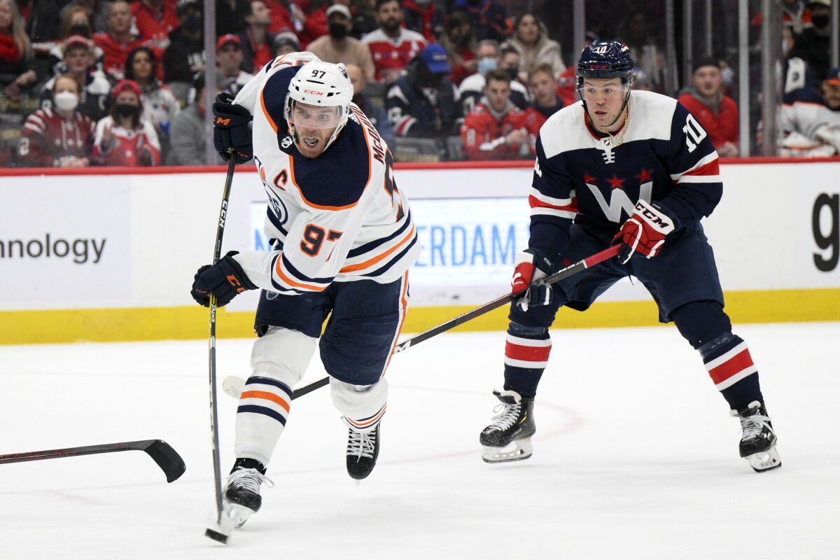 Edmonton Oilers center Connor McDavid (97) shoots the puck next to Washington Capitals right wing Daniel Sprong (10) during the second period of an NHL hockey game, Wednesday, Feb. 2, 2022, in Washington. (AP Photo/Nick Wass)