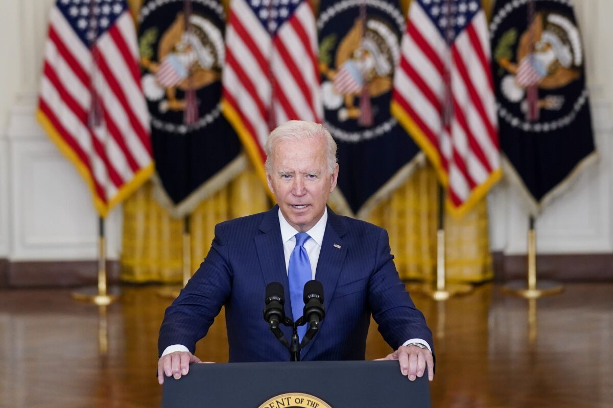 President Biden stands behind a podium and speaks into microphones.