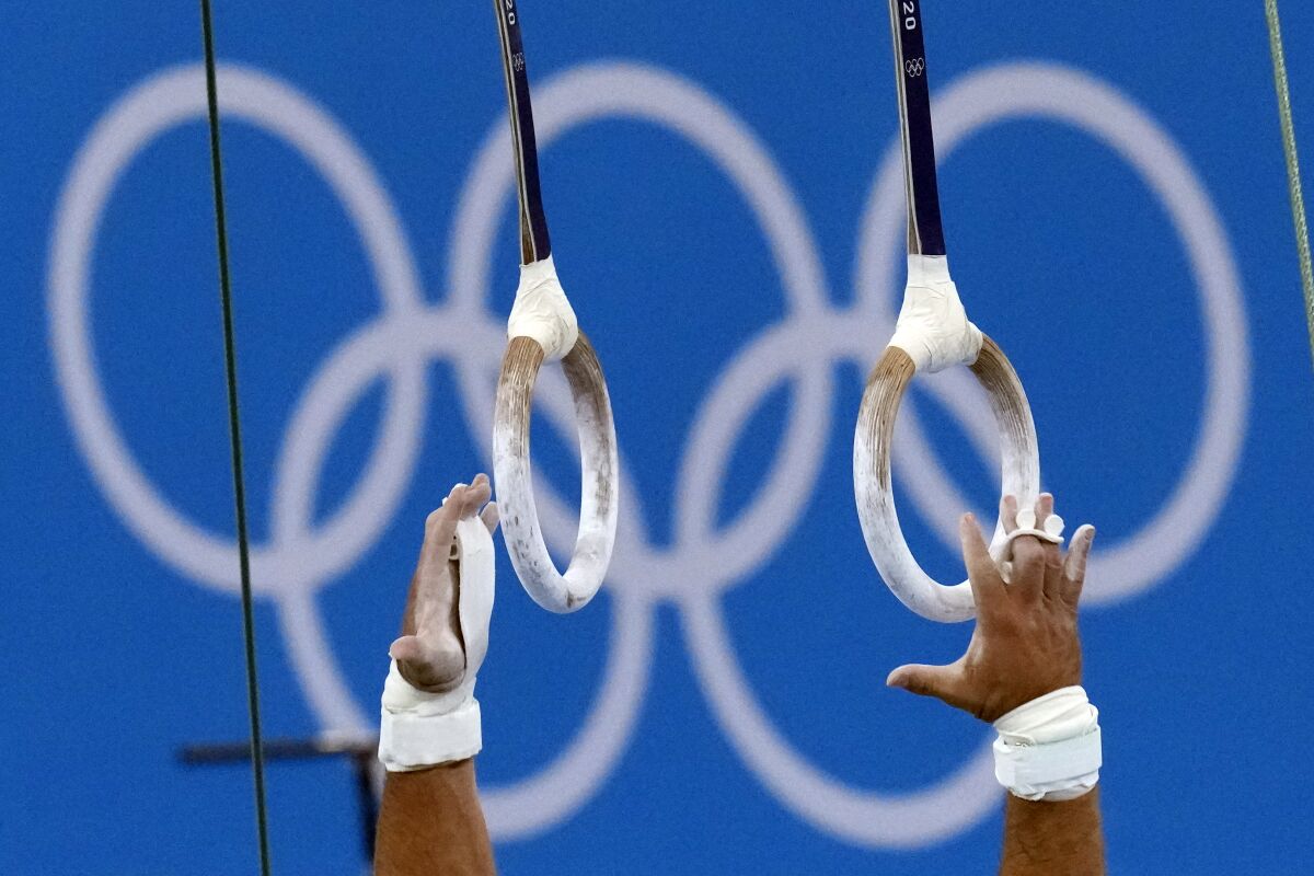 FILE - An athlete reaches for the rings during competition in artistic gymnastics at the 2020 Summer Olympics, Monday, Aug. 2, 2021, in Tokyo, Japan. Created to help protect athletes after the USA Gymnastics sexual abuse scandal, the sport’s international investigations agency has set new safeguarding standards with a view to the 2028 Los Angeles Olympics. (AP Photo/Gregory Bull, File)