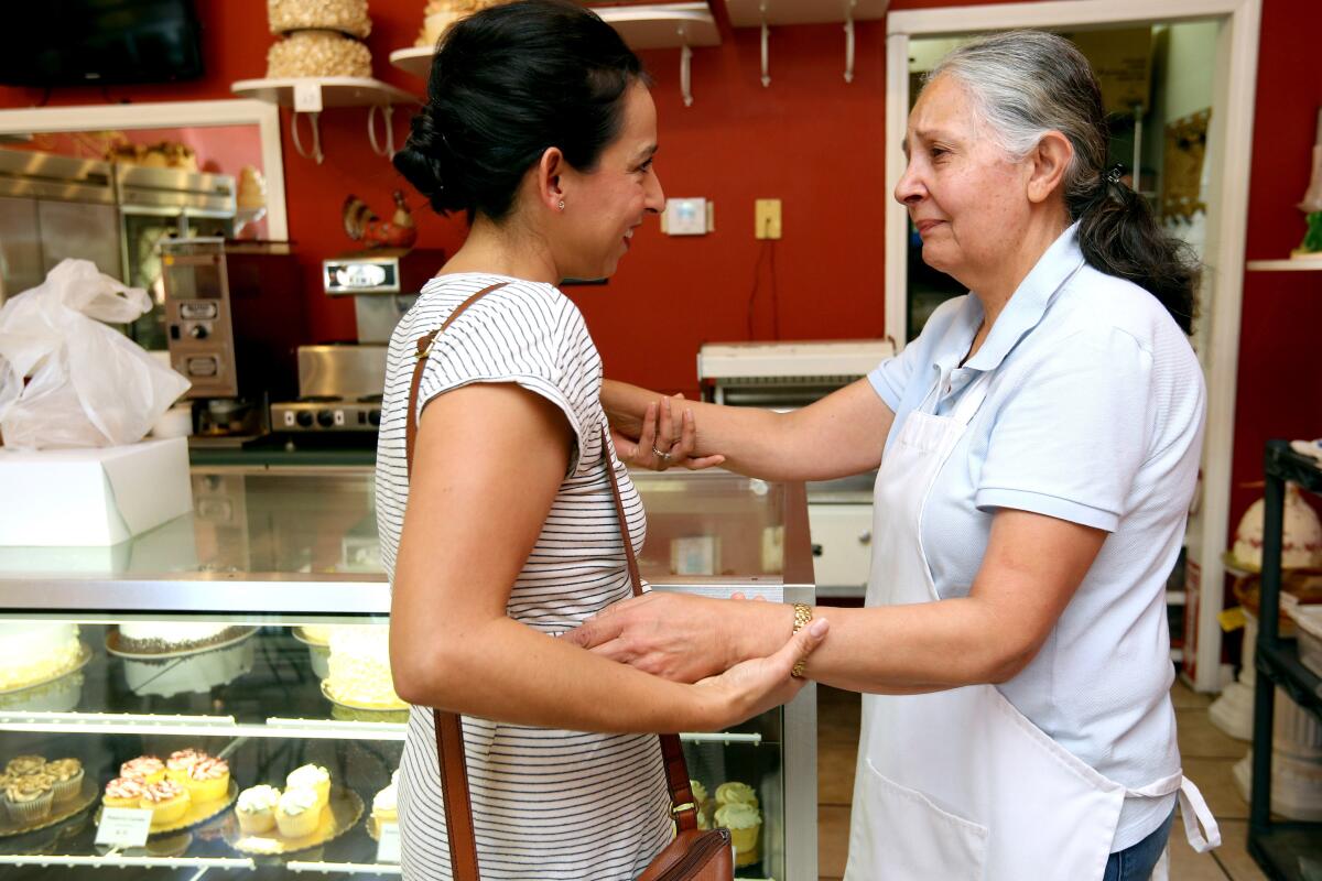 Cakery Bakery owner Zora Yasseri, right, gets a hug from customer Joey Kwon, 36 of La Cañada Flintridge, left, after Kwon found out the longtime baker and her husband will close shop on Dec. 15.