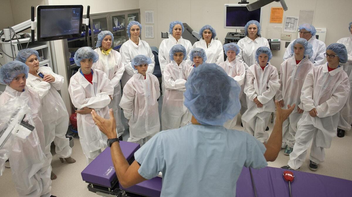A group of sixth-graders and adults listens as John Sigrist, bottom, of Intuitive Surgical discusses a Da Vinci Xi robotic surgical system in a lab at the Jeffrey M. Carlton Heart & Vascular Institute at Hoag Hospital in Newport Beach.