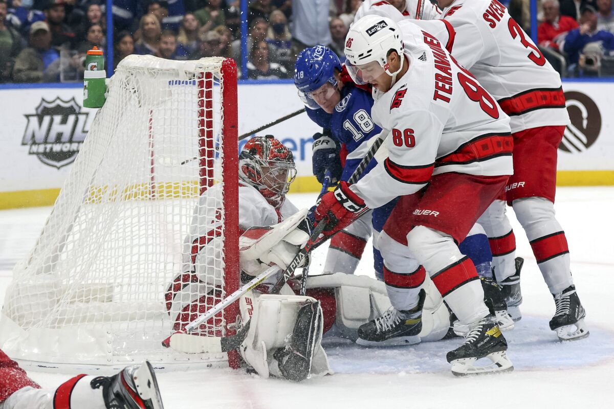 Tampa Bay Lightning's Ondrej Palat (18) of Czech Republic, battles against Carolina Hurricanes' Teuvo Teravainen (86), of Finland, for a puck under the pad of goaltender Frederik Andersen, of Denmark, during the second period of an NHL hockey game Tuesday, Nov. 9, 2021, in Tampa, Fla. (AP Photo/Mike Carlson)