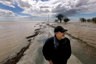 LEMOORE, CALIF. - MAR. 21, 2023. Agribusiness consultant Mark Grewel stands on a farm road that was flooded near Corcoran after recent heavy rains in the vast and fertile San Joaquin Valley. Grewel predicts that the area will experience greater flooding as more snow on local mountains melts with the advent of spring. Tulare Lake, a ghost lake that was drained more than 100 years ago, is now the location of large growing operations. It is filling up after a stormy winter. . (Luis Sinco / Los Angeles Times)