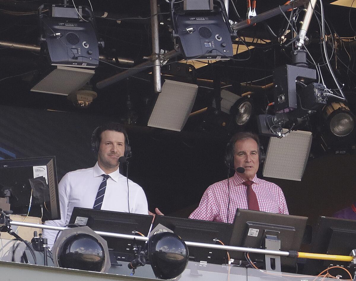Tony Romo and Jim Nantz work in the broadcast booth before an NFL football game