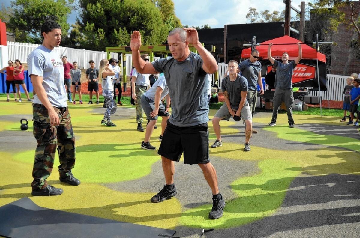 Kyle Markwalf of the Newport Beach Police Department participates in a police officers' challenge Saturday at The Playpen, the Newport-Mesa Family YMCA's new military-style obstacle course.