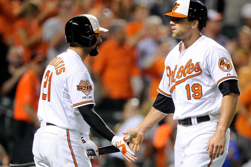 Baltimore's Nick Markakis (21) congratulates teammate Chris Davis (19) after he scored against Tampa Bay last month.