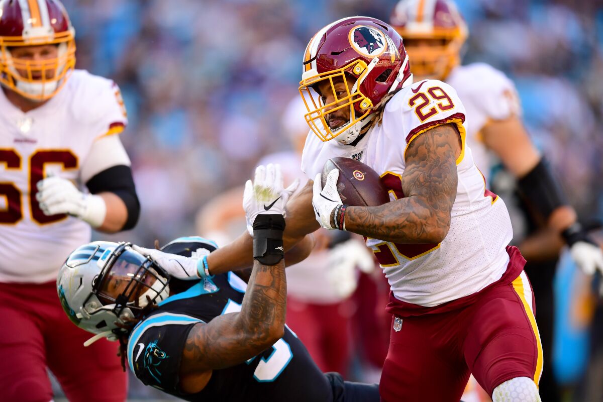Washington Redskins running back Derrius Guice stiff arms Carolina Panthers linebacker Shaq Thompson.