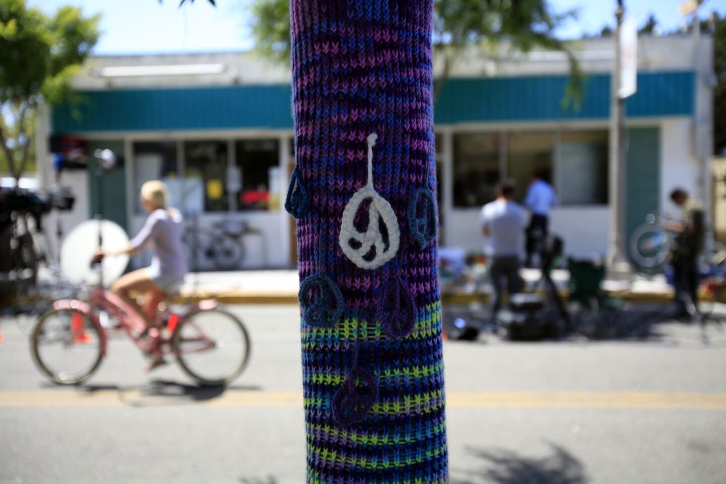 Knitted peace symbols hang from a tree across the street from of the I.V. Deli Mart in Isla Vista, a scene of part of the violent rampage Friday night.