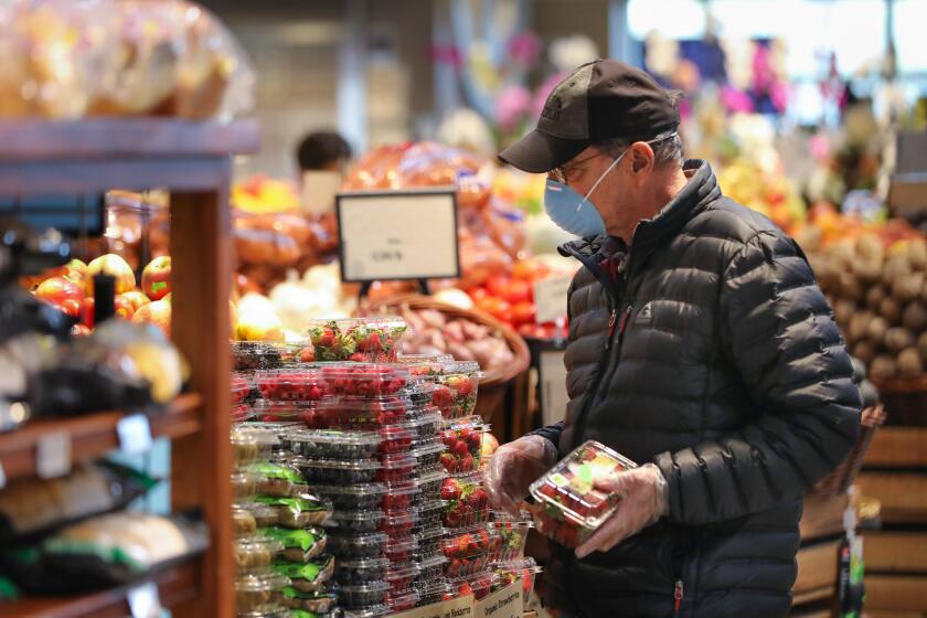 Conrad Kellenberger of North Park, wearing a face mask, shops in the Barons Market, North Park location, during the seniors-only time, one hour before the store opened to the general public, March 20, 2020 in San Diego, California. The seniors-only shopping is one of the many byproducts of the coronavirus outbreak, because older adults are one of the most vulnerable groups along with people with underlying heath issues are more susceptible to the virus.